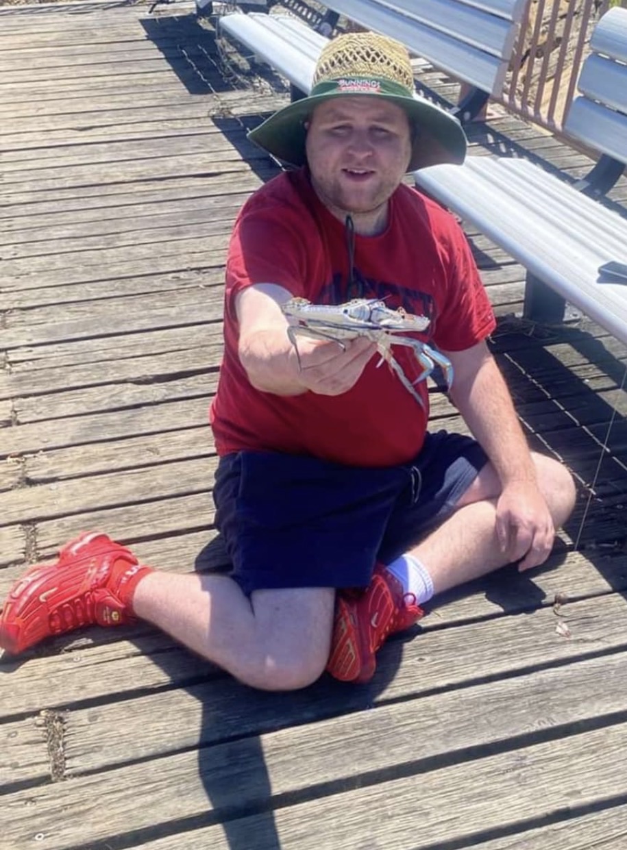 Sitting cross-legged on the jetty, proudly holding up a small crab
