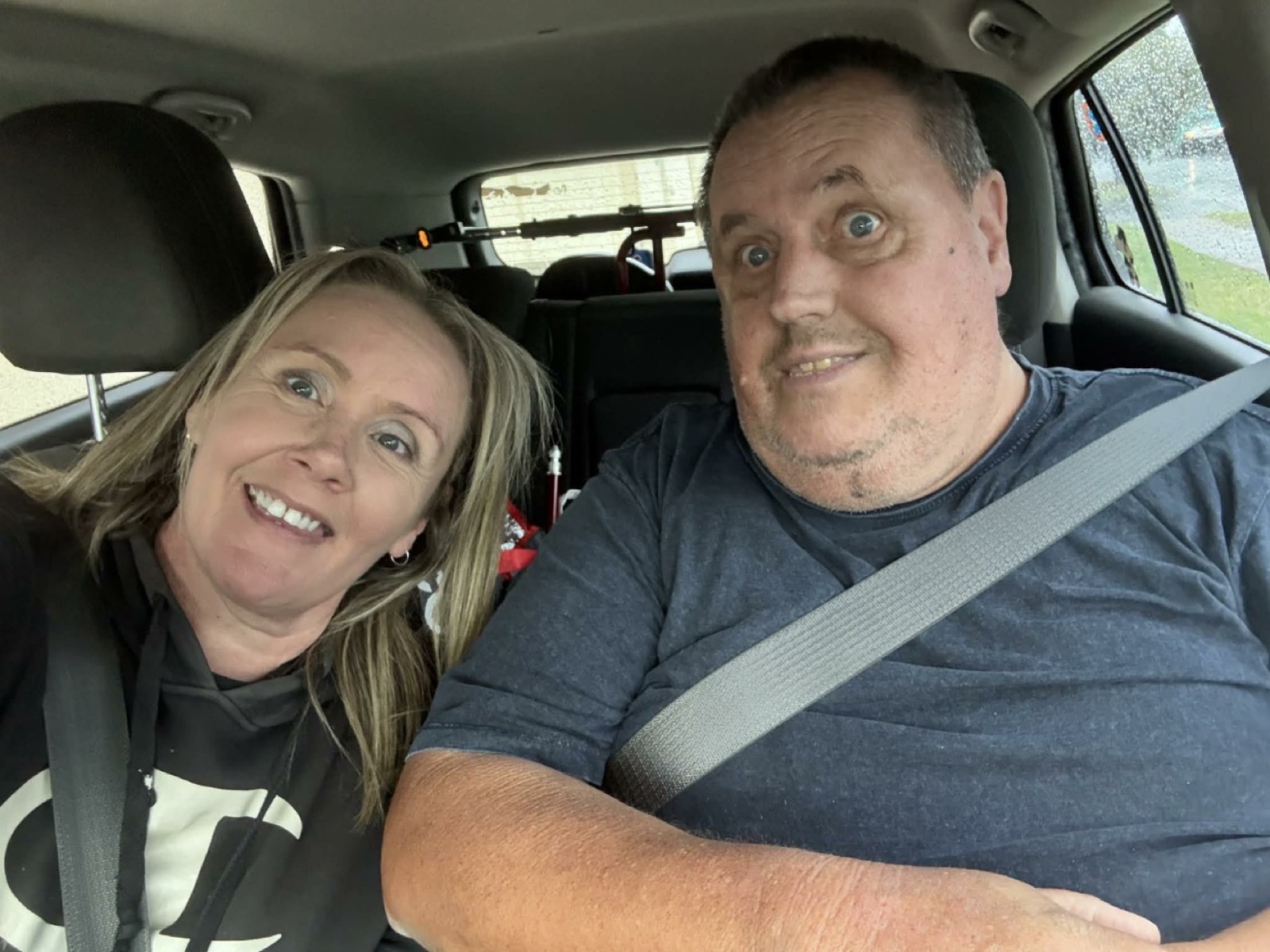 Two smiling faces in the car on a rainy day, off on the next adventure